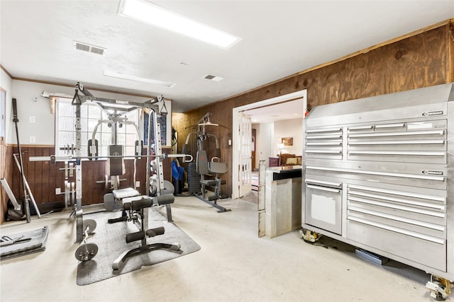 exercise area with wainscoting, visible vents, and wood walls