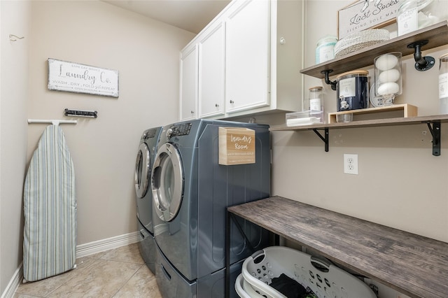 washroom with light tile patterned flooring, washing machine and clothes dryer, cabinet space, and baseboards