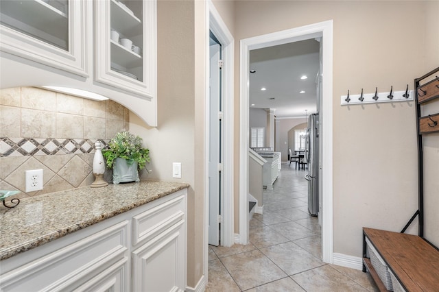 corridor with arched walkways, baseboards, light tile patterned flooring, ornate columns, and recessed lighting