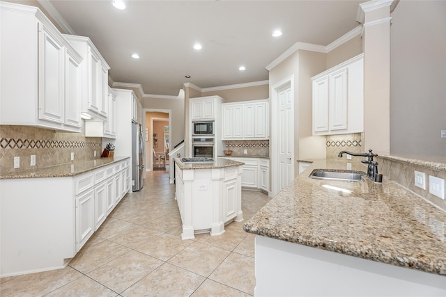 kitchen with stainless steel appliances, a sink, light stone countertops, and a center island