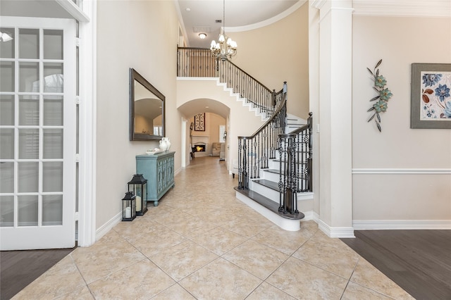 foyer entrance featuring light tile patterned floors, baseboards, arched walkways, ornamental molding, and a notable chandelier