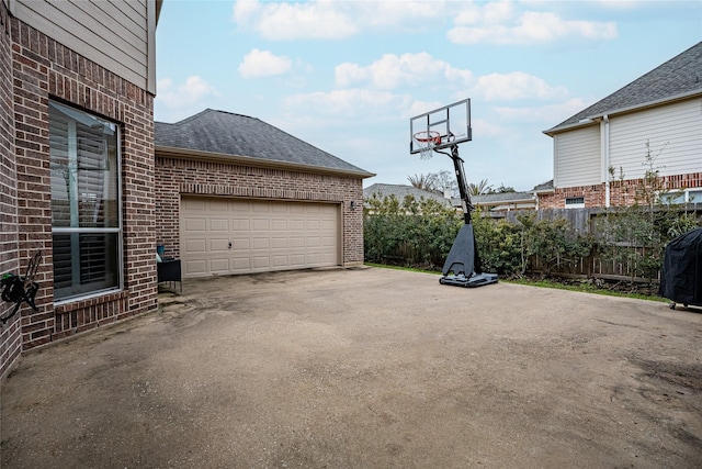 exterior space with driveway, a shingled roof, fence, and brick siding