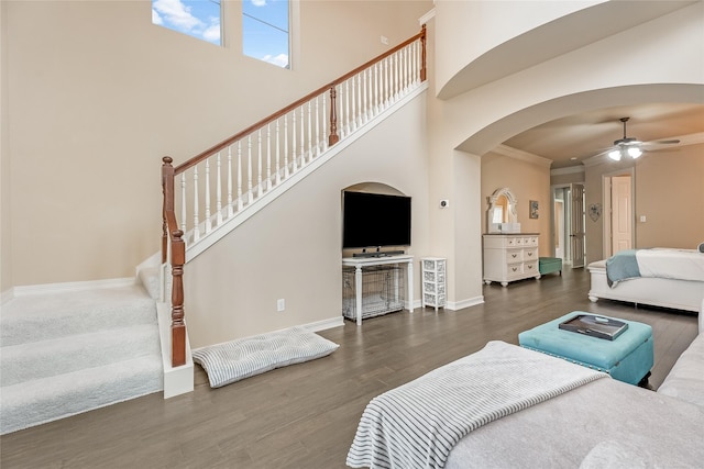 bedroom with arched walkways, dark wood-style flooring, a high ceiling, ornamental molding, and baseboards