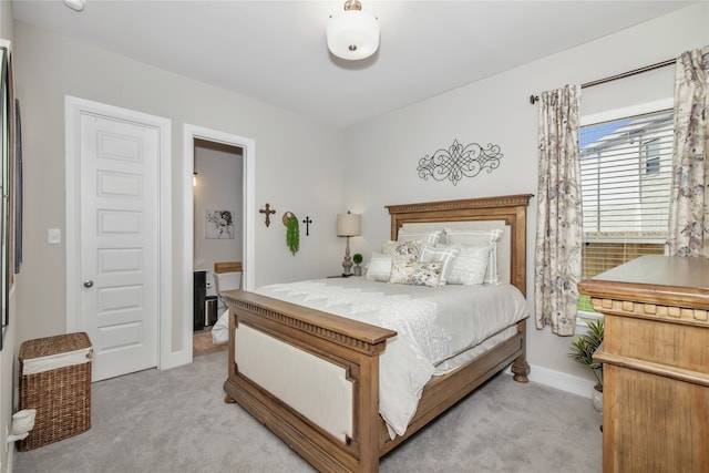 bedroom featuring baseboards, connected bathroom, and light colored carpet