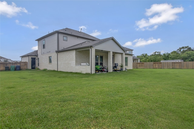 back of property with brick siding, a fenced backyard, and a yard