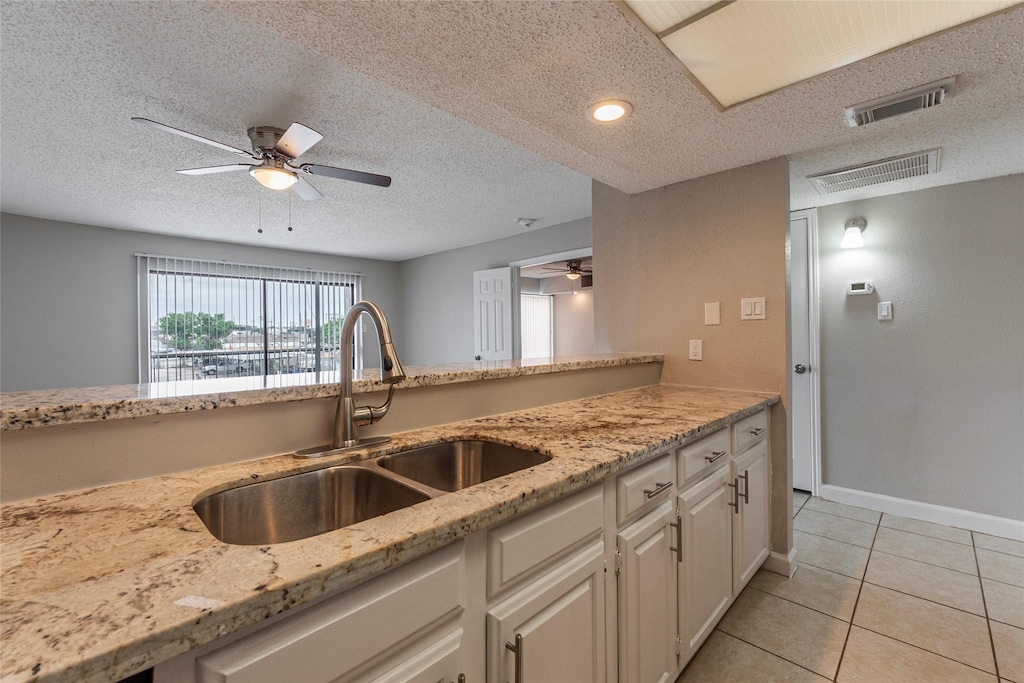 kitchen with white cabinetry, a sink, visible vents, and light tile patterned floors