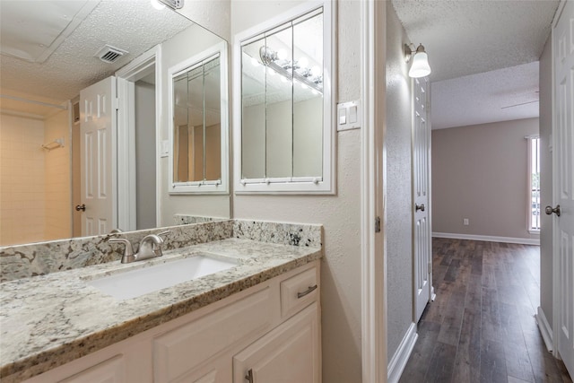 full bathroom with visible vents, a textured ceiling, baseboards, and wood finished floors