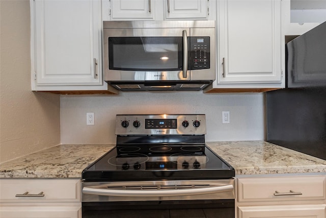 kitchen with stainless steel appliances, white cabinets, and light stone countertops