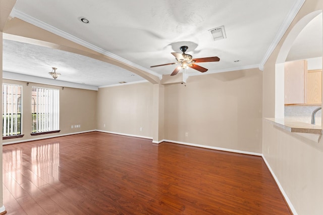 unfurnished living room featuring baseboards, arched walkways, a ceiling fan, dark wood-style floors, and crown molding