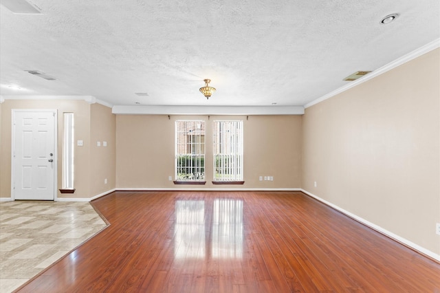 unfurnished room with visible vents, crown molding, hardwood / wood-style flooring, and baseboards