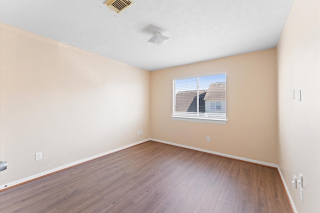 unfurnished room with baseboards, visible vents, and wood finished floors