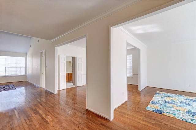 spare room with light wood finished floors, crown molding, and baseboards