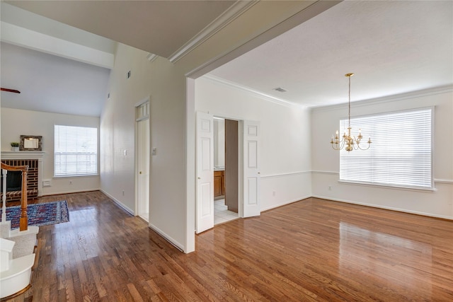 interior space featuring a chandelier, ornamental molding, a fireplace, and wood finished floors