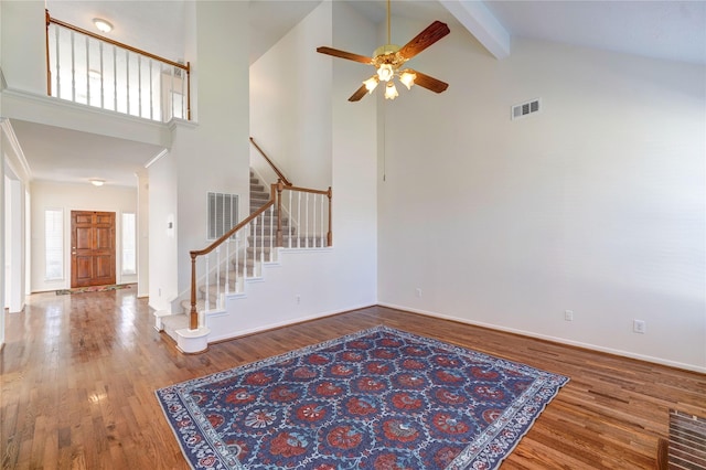 entrance foyer with visible vents, beam ceiling, wood finished floors, and stairs