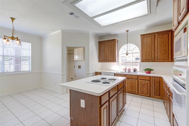 kitchen with visible vents, light countertops, light tile patterned flooring, brown cabinetry, and white appliances