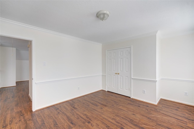 spare room featuring baseboards, attic access, wood finished floors, and crown molding