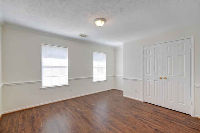 spare room with visible vents, baseboards, ornamental molding, dark wood-style floors, and a textured ceiling