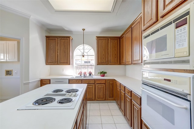 kitchen with crown molding, decorative light fixtures, light countertops, brown cabinets, and white appliances