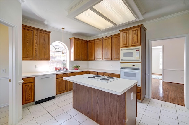 kitchen featuring crown molding, light countertops, light tile patterned floors, brown cabinets, and white appliances