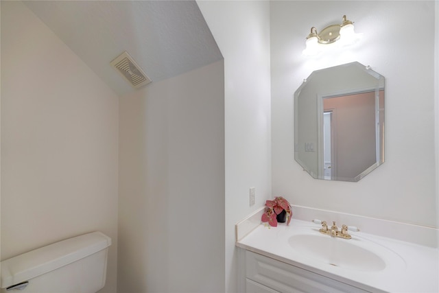 bathroom with vanity, toilet, and visible vents