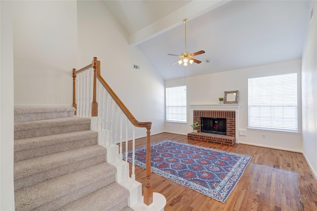 living area with stairs, beam ceiling, wood finished floors, and a wealth of natural light