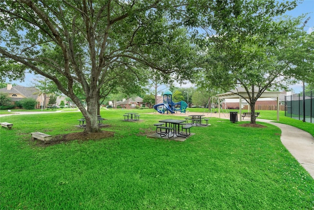 view of property's community featuring a lawn, playground community, and fence