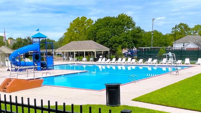 pool with a patio, a water slide, and fence