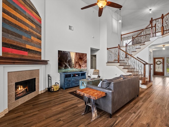 living area featuring stairway, dark wood-style flooring, a fireplace, and visible vents