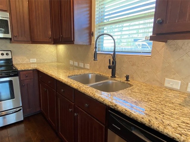 kitchen featuring light stone countertops, tasteful backsplash, appliances with stainless steel finishes, and a sink