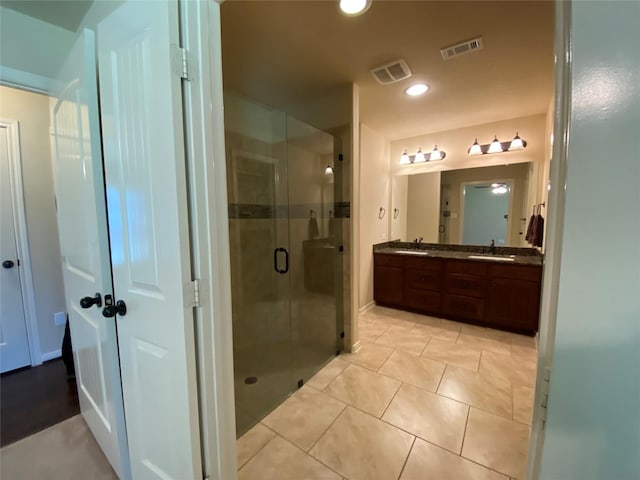 bathroom with a stall shower, a sink, and visible vents