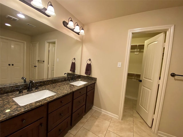 full bath featuring double vanity, a sink, visible vents, and baseboards