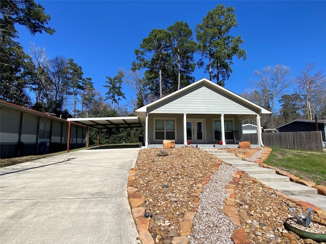 view of front of house with a carport, concrete driveway, a porch, and fence