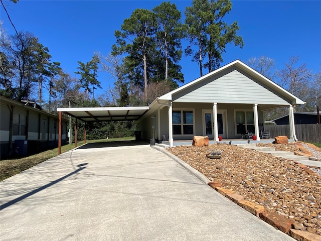 view of front of house featuring a carport, covered porch, fence, and concrete driveway