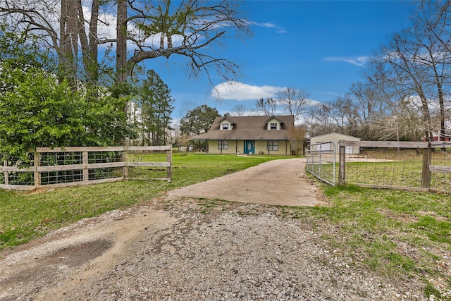 view of front of property with dirt driveway, a front lawn, fence, and a gate