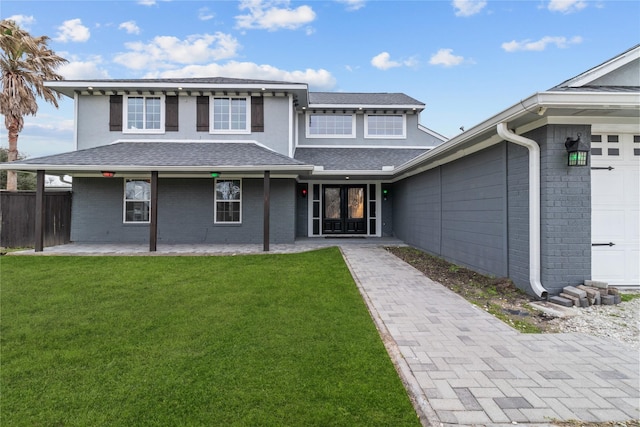 view of front facade featuring a patio area, roof with shingles, a front lawn, and brick siding