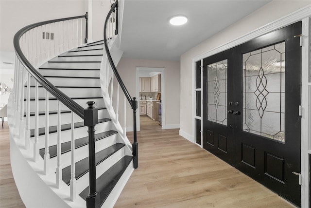 foyer featuring visible vents, baseboards, french doors, stairway, and light wood-type flooring