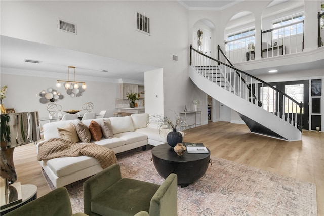 living room with ornamental molding, visible vents, stairway, and wood finished floors