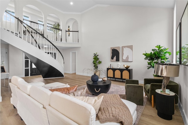 living area with high vaulted ceiling, light wood-style flooring, stairway, and baseboards