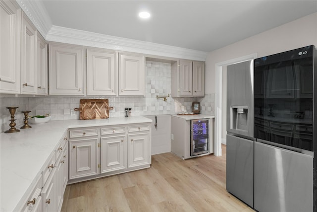 kitchen with beverage cooler, tasteful backsplash, light wood-type flooring, refrigerator with glass door, and white cabinetry