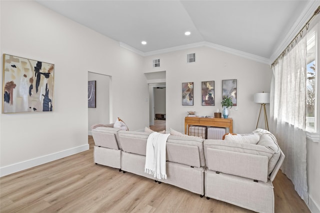 living area with a healthy amount of sunlight, light wood-style floors, visible vents, and vaulted ceiling