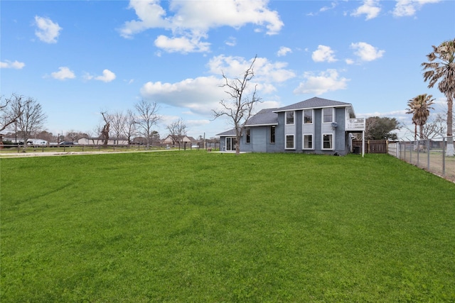 view of yard featuring fence and a balcony