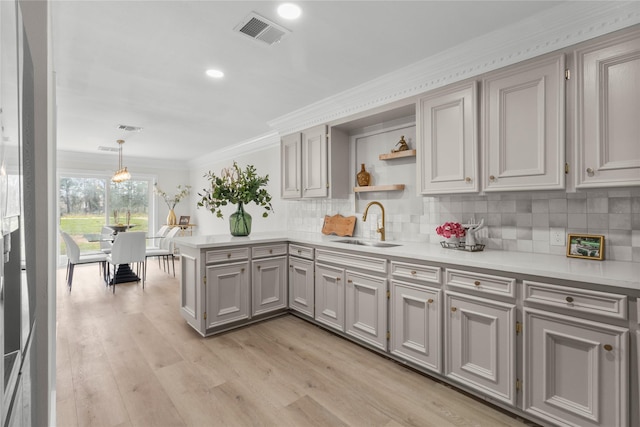 kitchen featuring visible vents, decorative light fixtures, light countertops, open shelves, and a sink