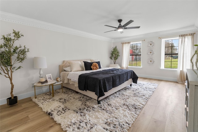 bedroom featuring ornamental molding, light wood-type flooring, baseboards, and a ceiling fan