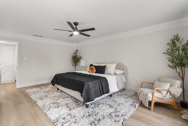 bedroom with baseboards, light wood-style flooring, visible vents, and crown molding