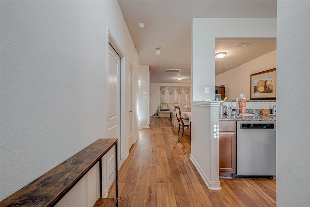 corridor with light wood finished floors, baseboards, and visible vents