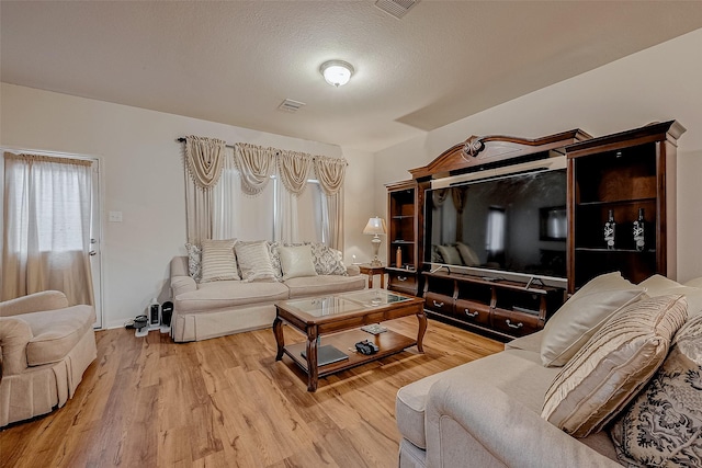 living area featuring light wood-style floors, visible vents, and a textured ceiling