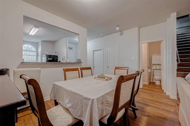 dining area with light wood finished floors, stairs, and baseboards