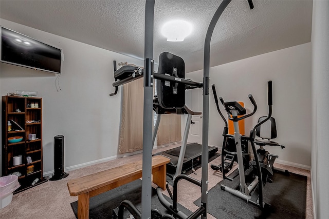 exercise room featuring carpet floors, baseboards, and a textured ceiling