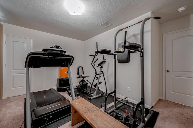 exercise room featuring baseboards, visible vents, a textured ceiling, and carpet flooring