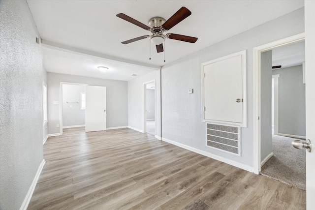 spare room featuring light wood finished floors, visible vents, and baseboards